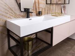 Le lavabo blanc en Mineralguss repose sur une structure suspendue en aluminium, laissant le siphon visible.